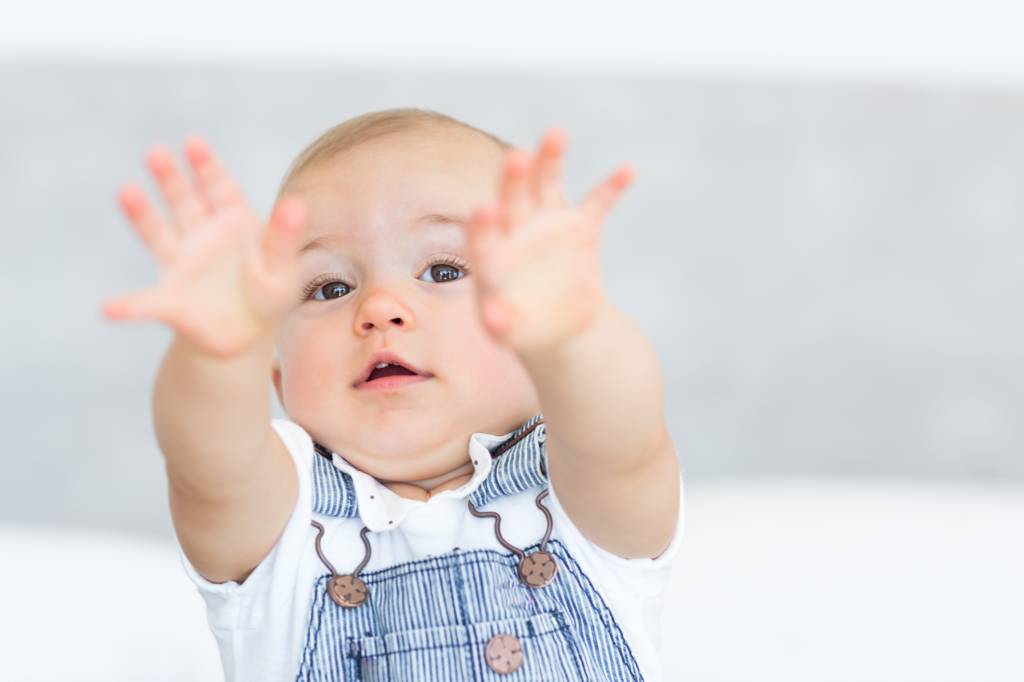 Bebê de um aninho querendo colo da mãe