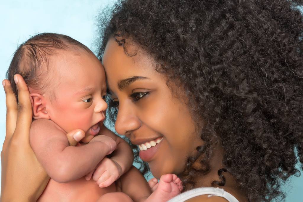 Mãe segura filho recém nascido e sorri