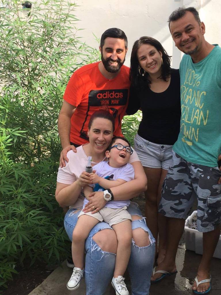 Maria Eduarda Tassi Martins e sua família na ABRACE ao redor de pés de maconha