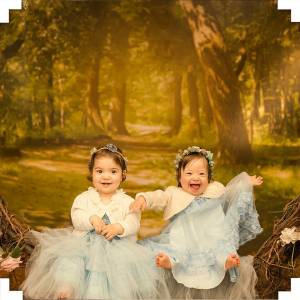 Duas meninas, de vestido azul, sentadas posando para uma foto