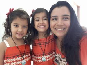 Gêmeas juntas com a mãe, todas de vermelho, posando para a foto sorrindo