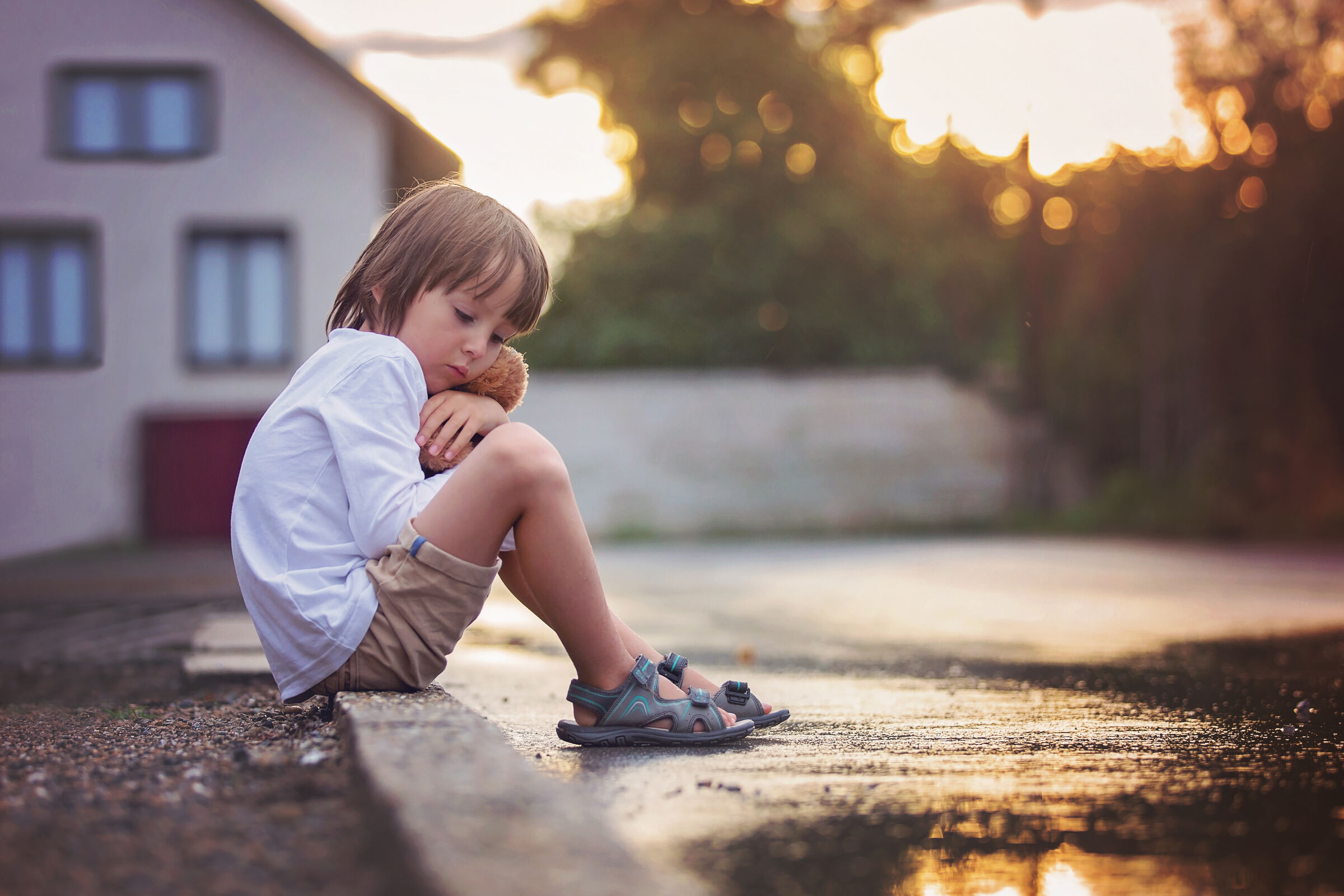 Criança triste sentada na calçada da rua