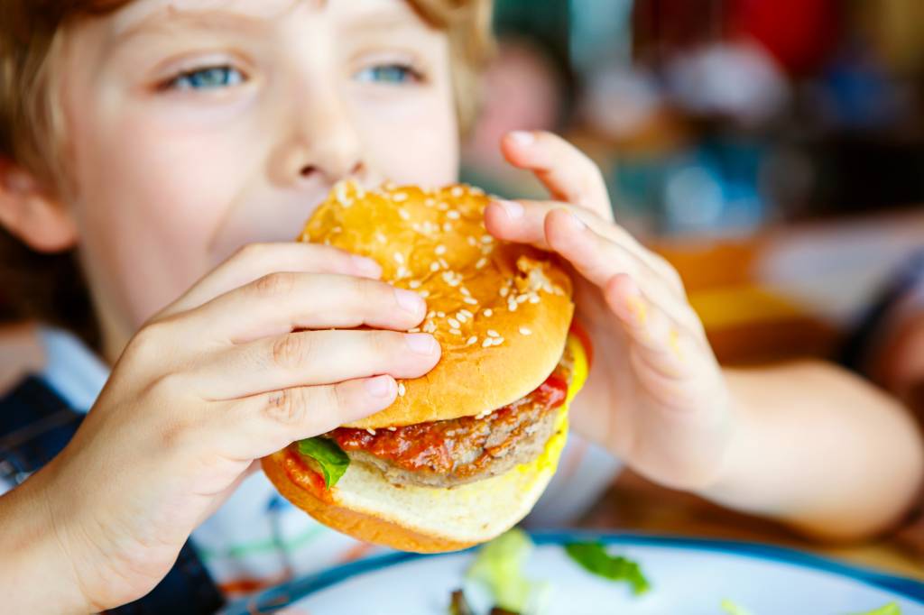 menino comendo hamburguer