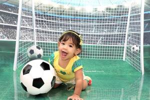 Bebê fantasiado com verde e amarelo para ensaio com o tema de Copa do Mundo