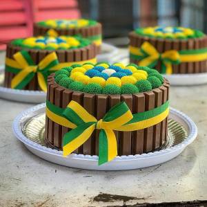 Bolo de chocolate com brigadeiros em cima enrolados com granulados verde e amarelo