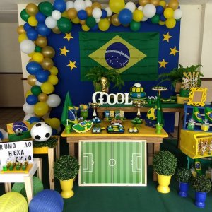 Decoração baseada em Copa do Mundo, com balões verde e amarelo, bolo em formato de bola