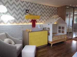 Quarto infantil com detalhes especialmente em amarelo, com cômoda e berço