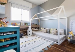 Quarto infantil decorado com uma cama montessori branca e tapete branco, com cômoda azul