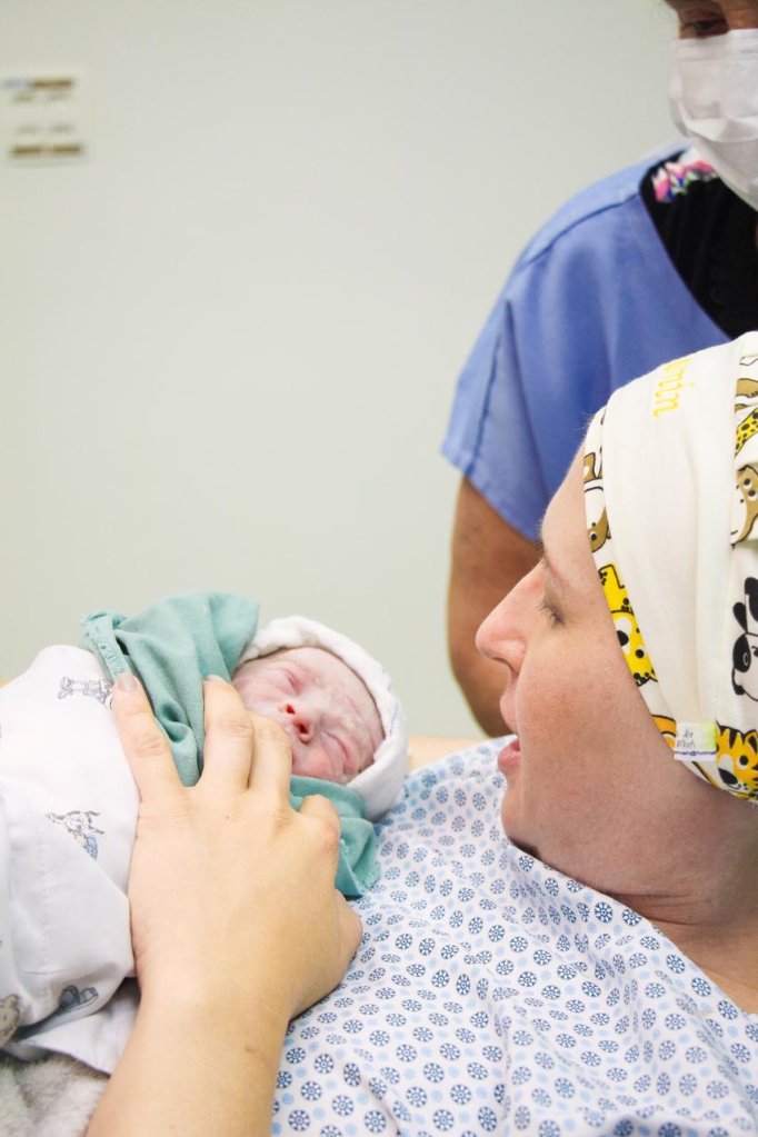 mulher em uma cama de hospital, segurando um bebê no colo