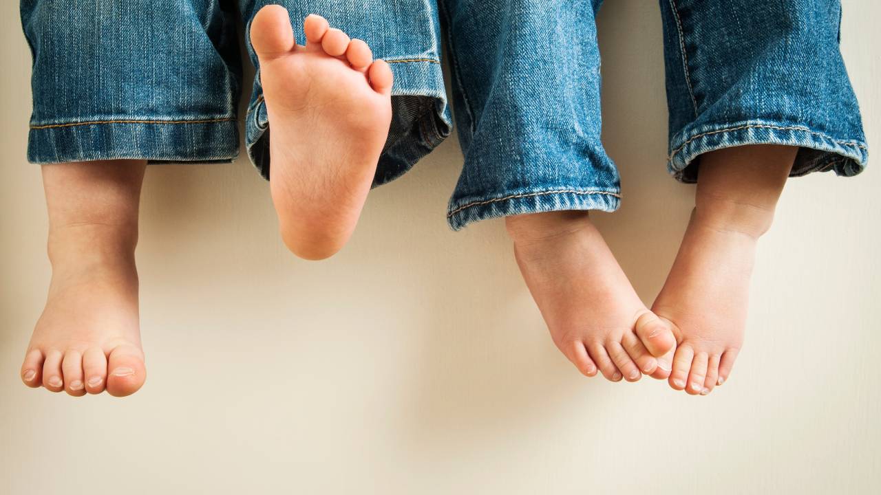 close em pés descalços de duas crianças usando calça jeans