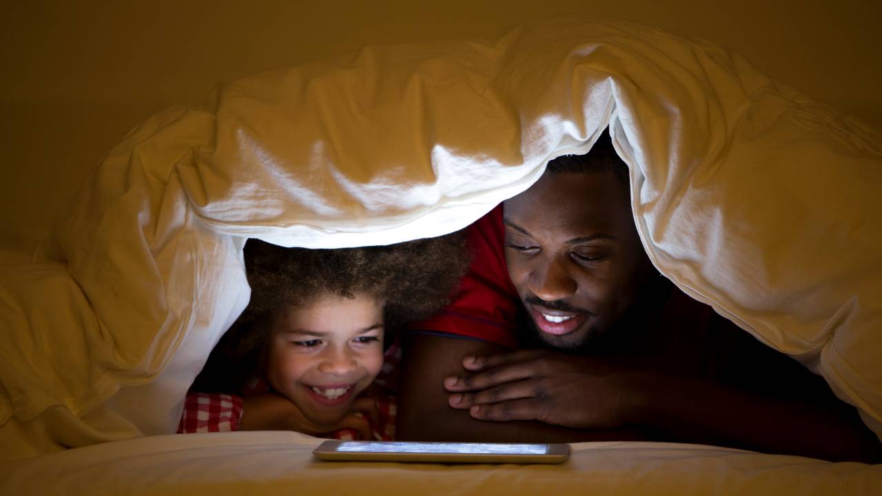 Pai e filha lendo no tablet