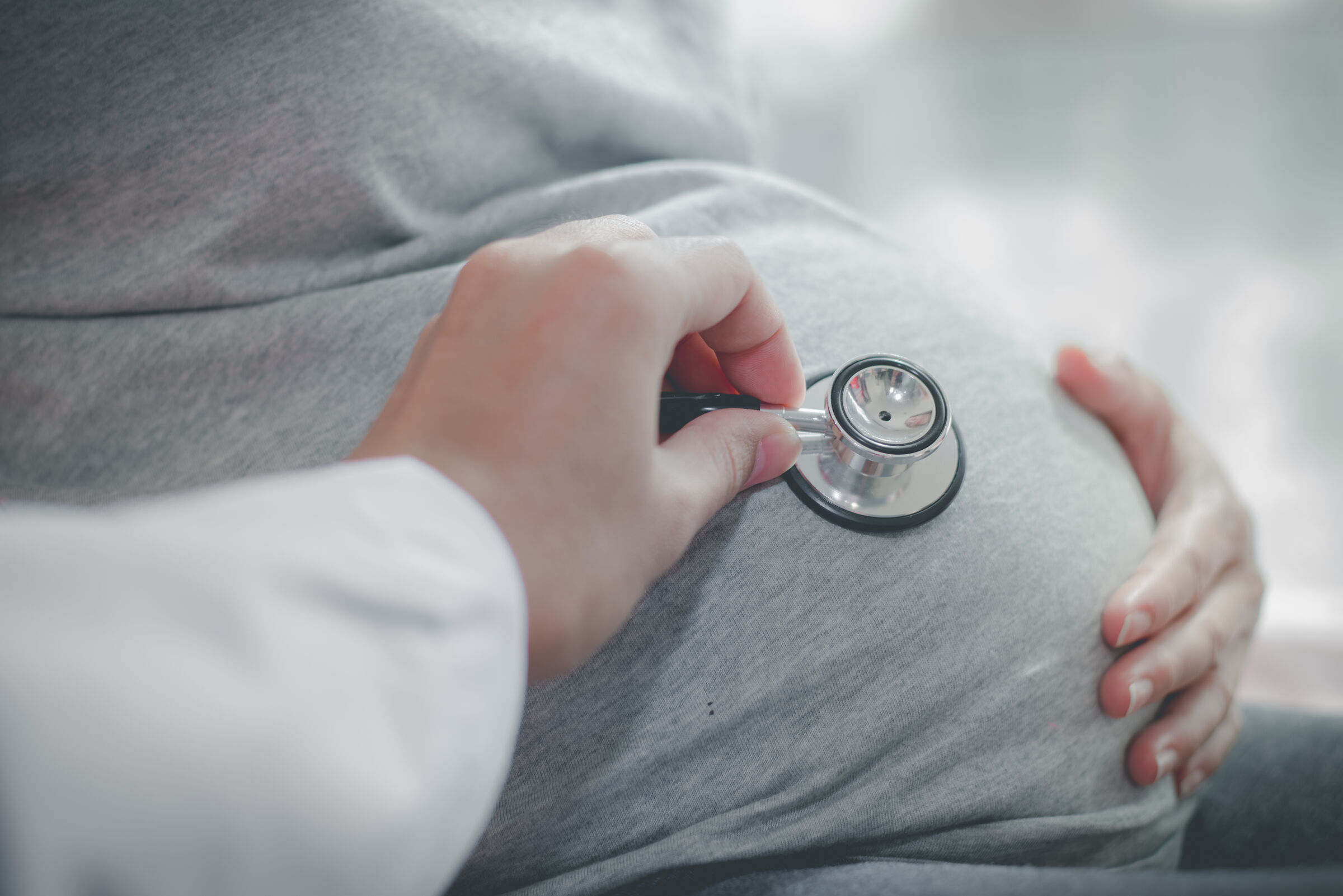 médico encosta estetoscópio na barriga de uma grávida