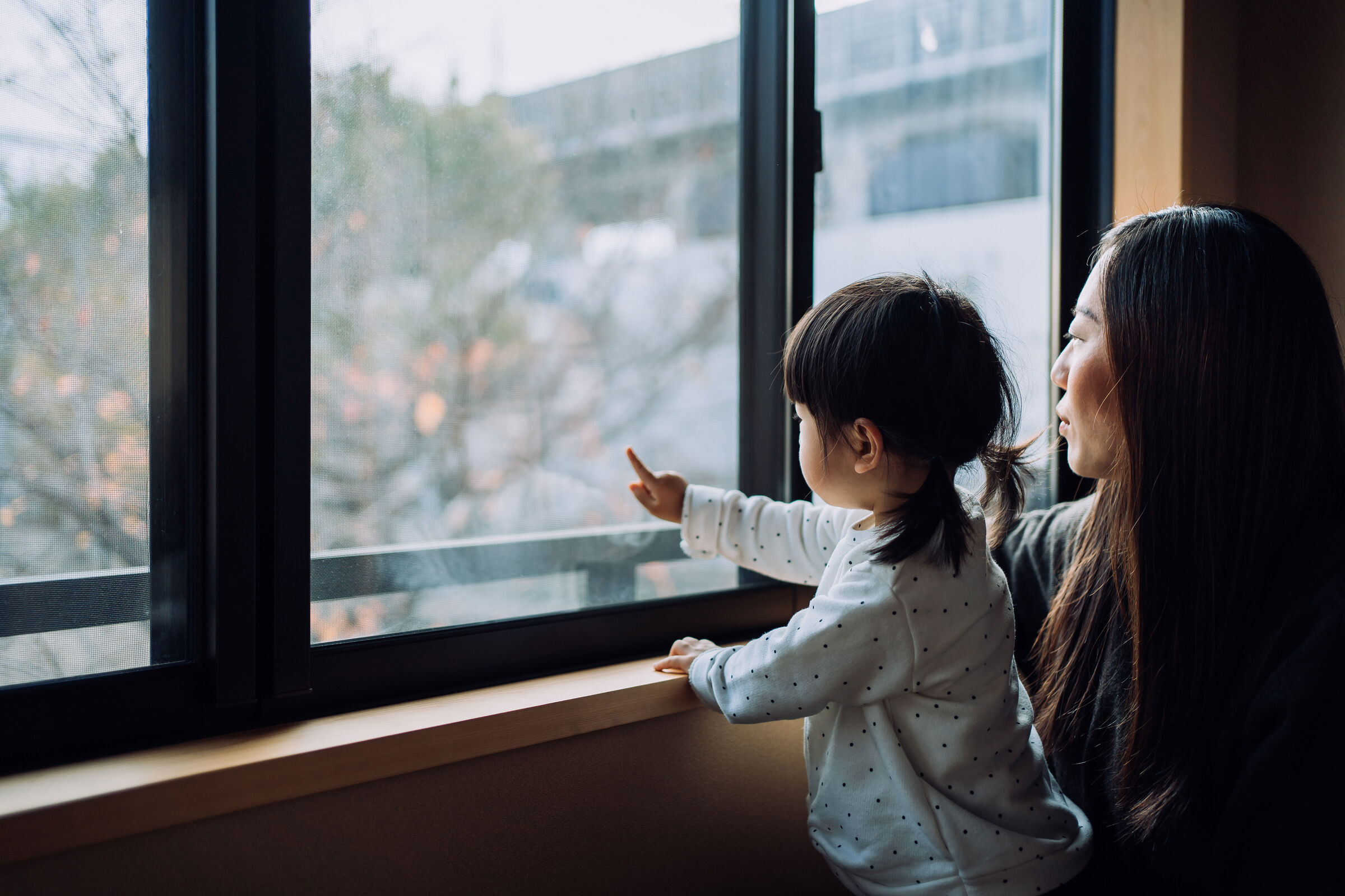 menina e mãe olhando pela janela