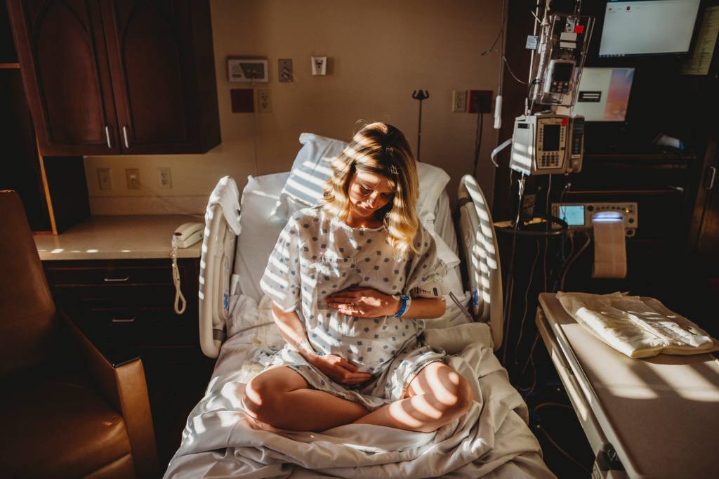 mulher grávida sentada em uma cama de hospital