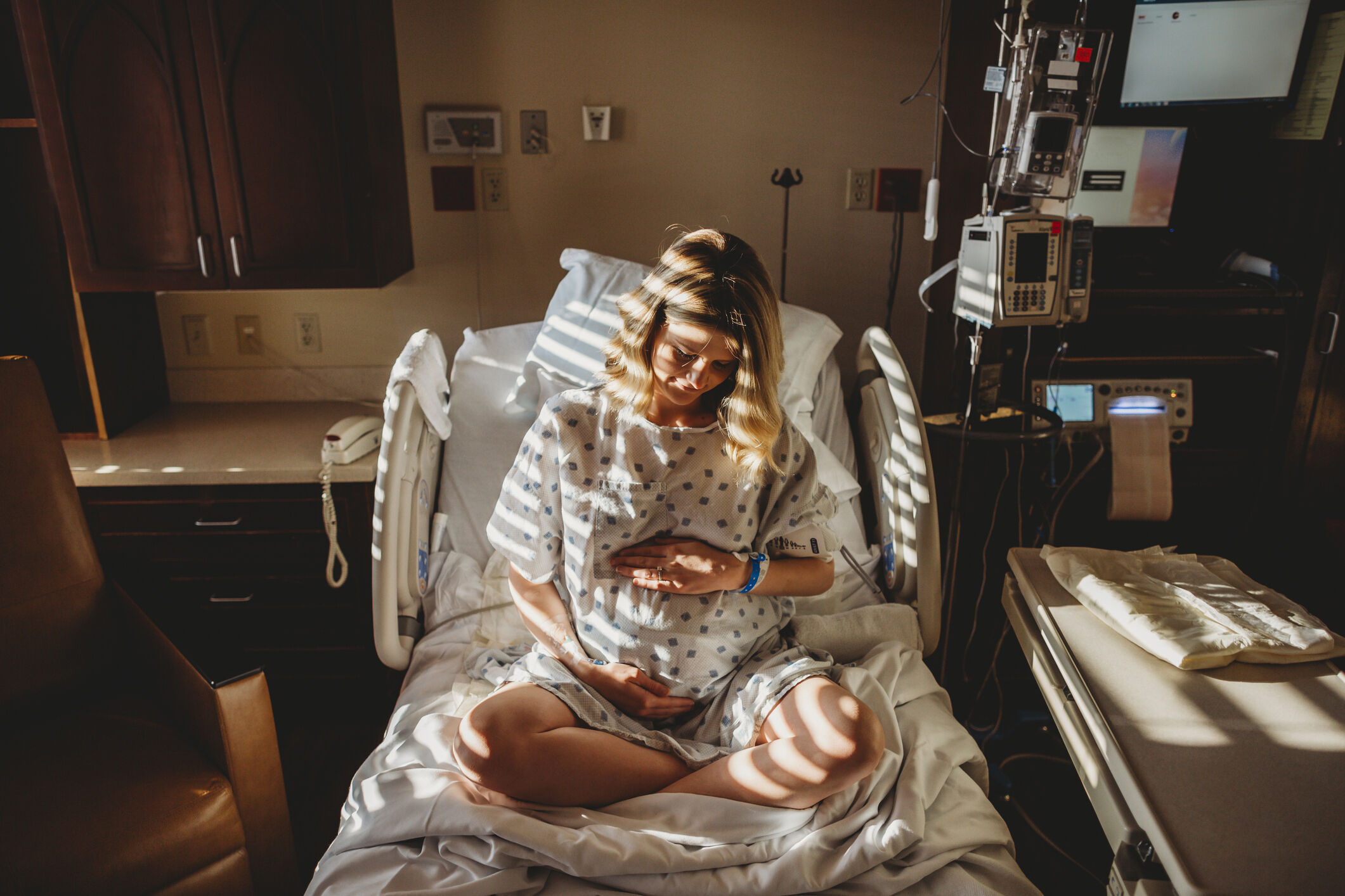 grávida sentada em cama de hospital