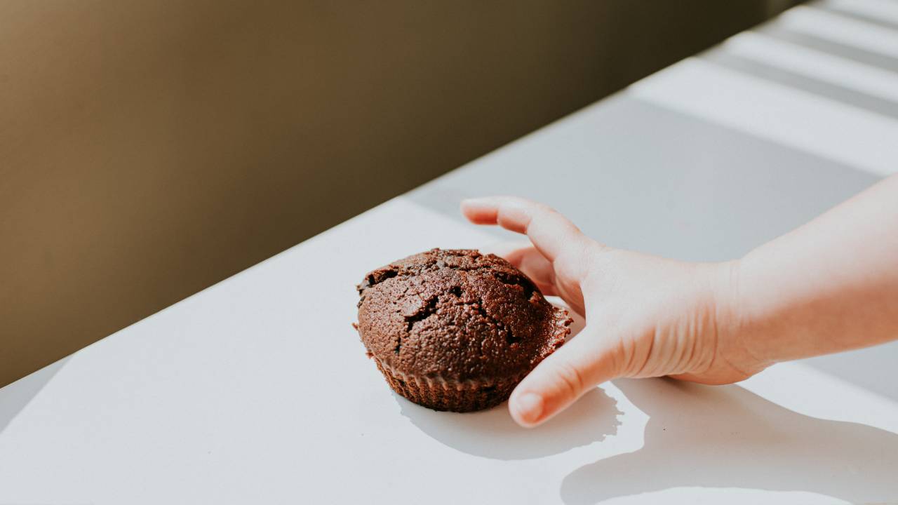 Mão de criança alcançando cupcake