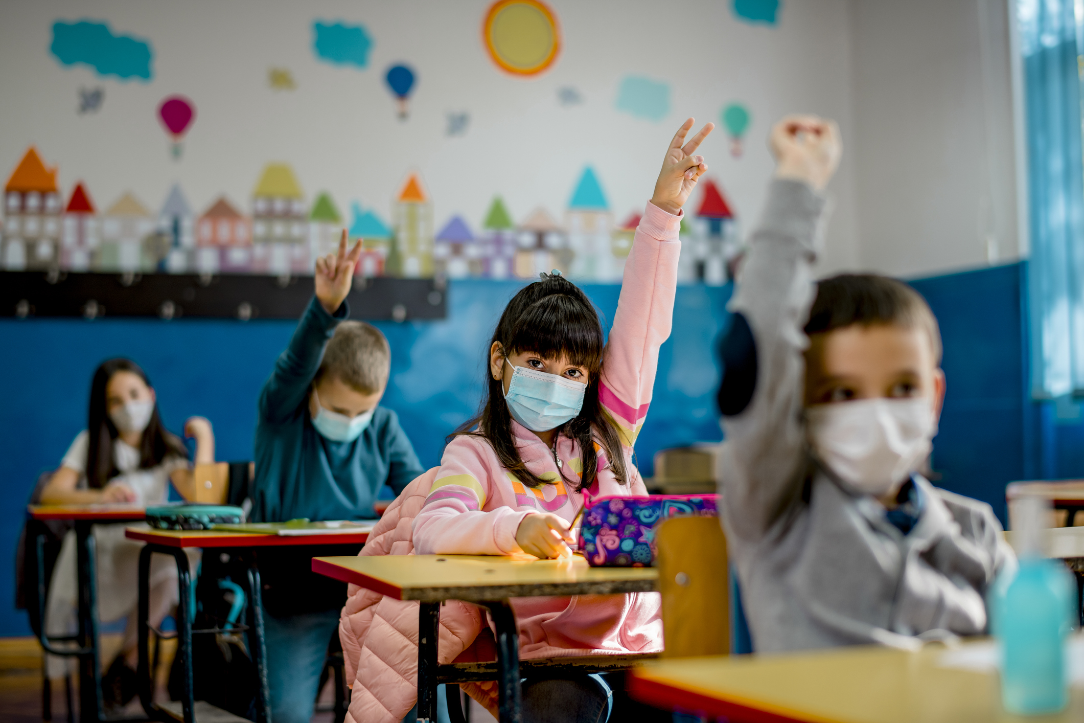 Crianças usando máscara em sala de aulta