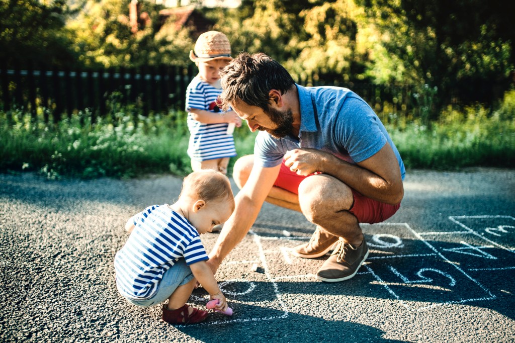 Pai brincando de amarelinha com filhos