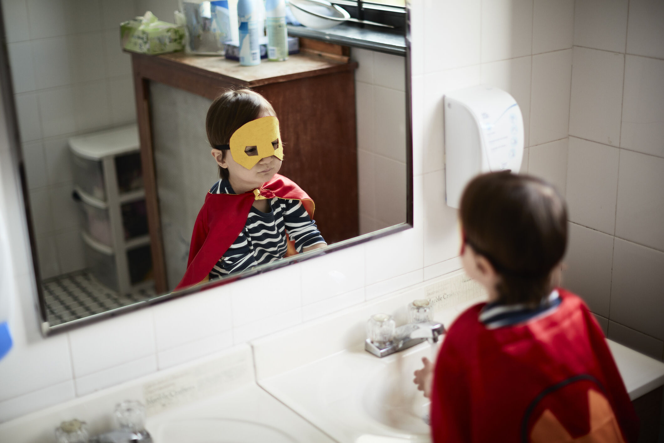 Menino usando máscara se olhando no espelho