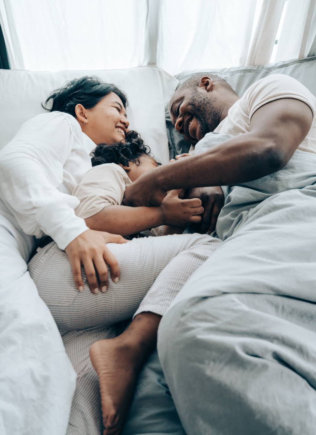 Família-se-abraçando-enquanto-estão-deitados-na-cama Família-se-abraçando-enquanto-estão-deitados-na-cama