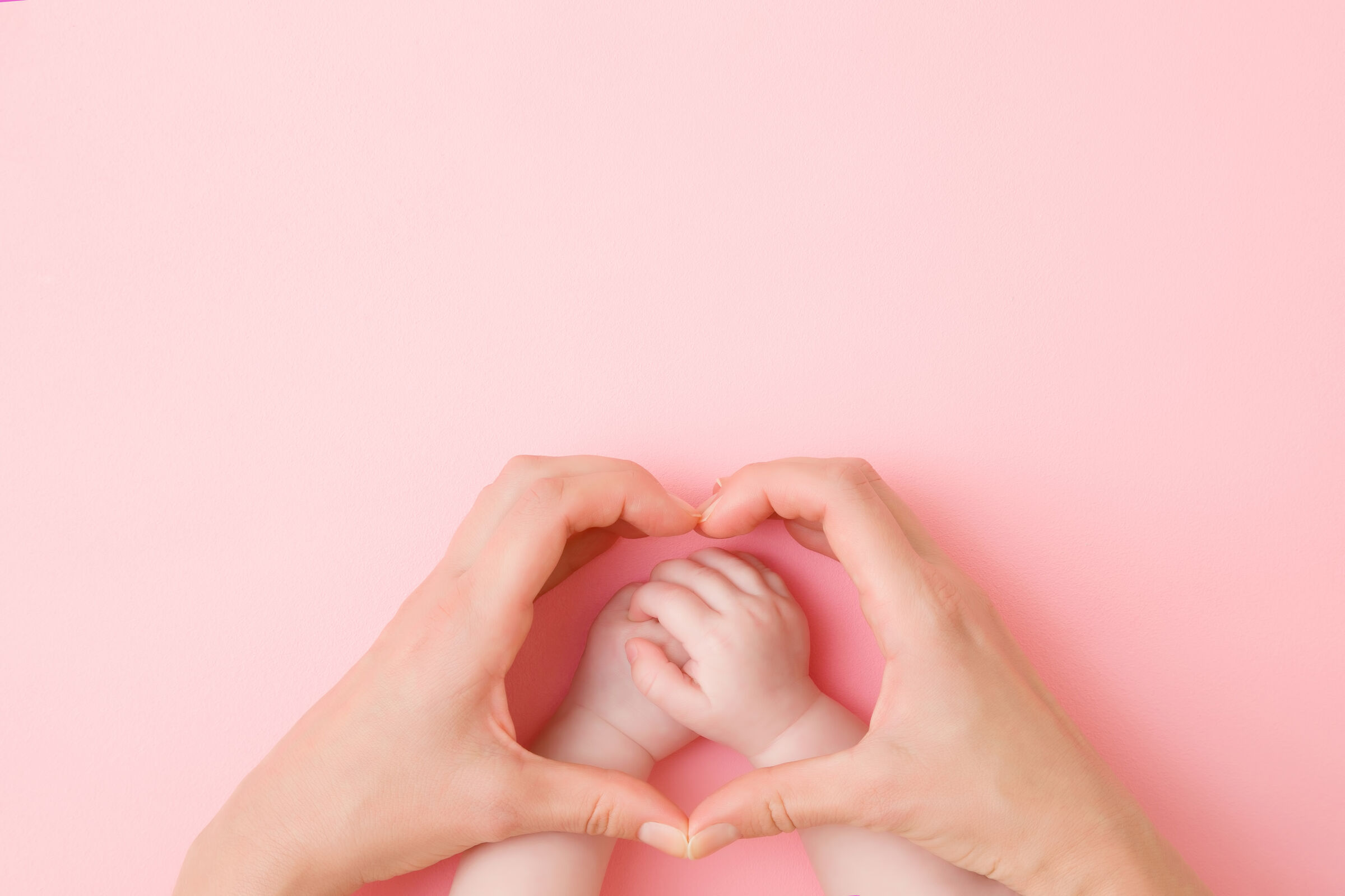 Mãos adultas e mãos de bebê em formato de coração
