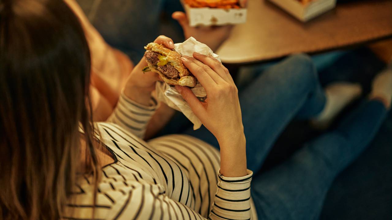 Alimentação da grávida. Comendo hambúrguer. Fast food.