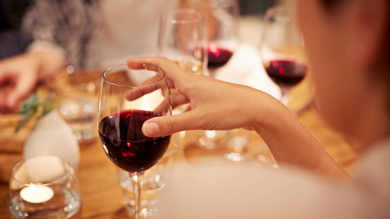 Mulher segurando o copo com vinho tinto