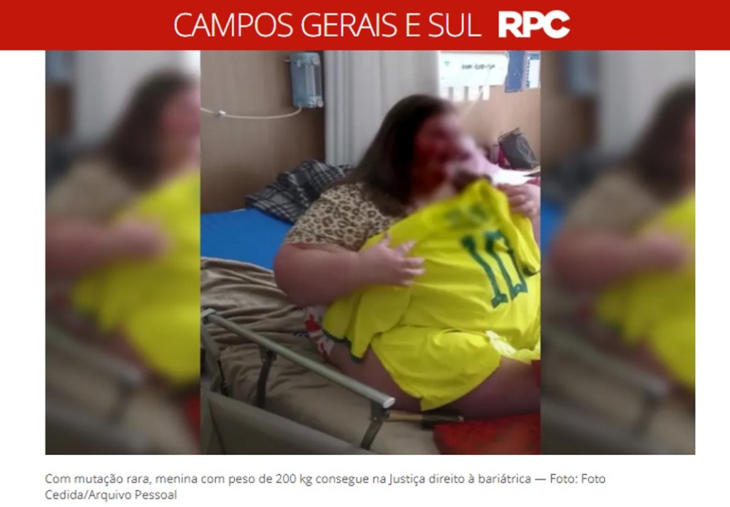 Na foto, uma menina obesa, cujo rosto está borrado para não ser identificada, está sentada sobre a cama de hospital. Está com uma camisa 10 da seleção brasileira, amarela, sobre o corpo. Ela parece sorrir.