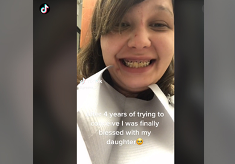 Printscreen de um vídeo de Marissa Green no tik tok. É possível vê-la sorrindo para mostrar os dentes muito deteriorados, principalmente na arcada superior. Ela tem uma franja de lado, os cabelos loiros, pele clara e está usando um avental branco de dentista.