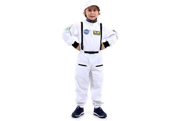 garoto em pé, com as mãos na cintura e macacão de astronauta