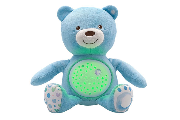 Urso de pelúcia azul. Sua barriga é de plástico e contém orifícios em forma de estrela. Por trás do plástico, há uma luz