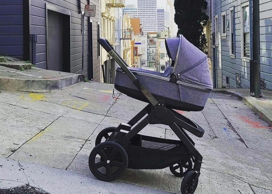 Imagem do carrinho Ella, cinza e preto, parado sozinho em uma descida na rua.