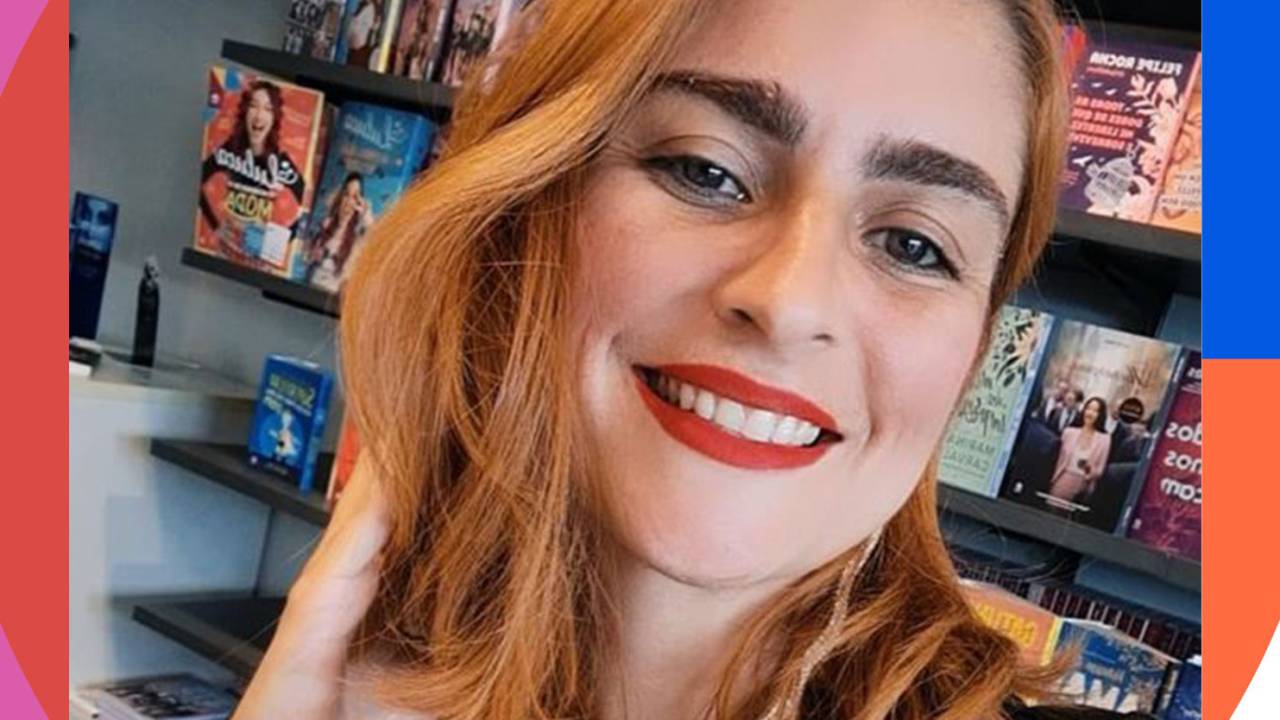mulher sorrindo para a câmera com uma das mãos na lateral da cabeça, sobre o cabelo