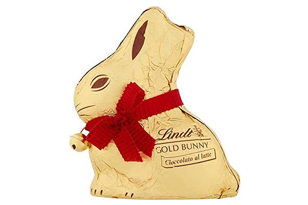 chocolate em forma de coelho embalado em um papel dourado e um lado vermelho no pescoço
