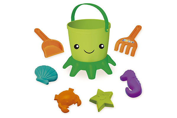 ao centro, um balde de brinquedo em formato de polvo. Ao redor dele, pás e formas plásticas em forma de estrela, concha, cavalo marinho e siri