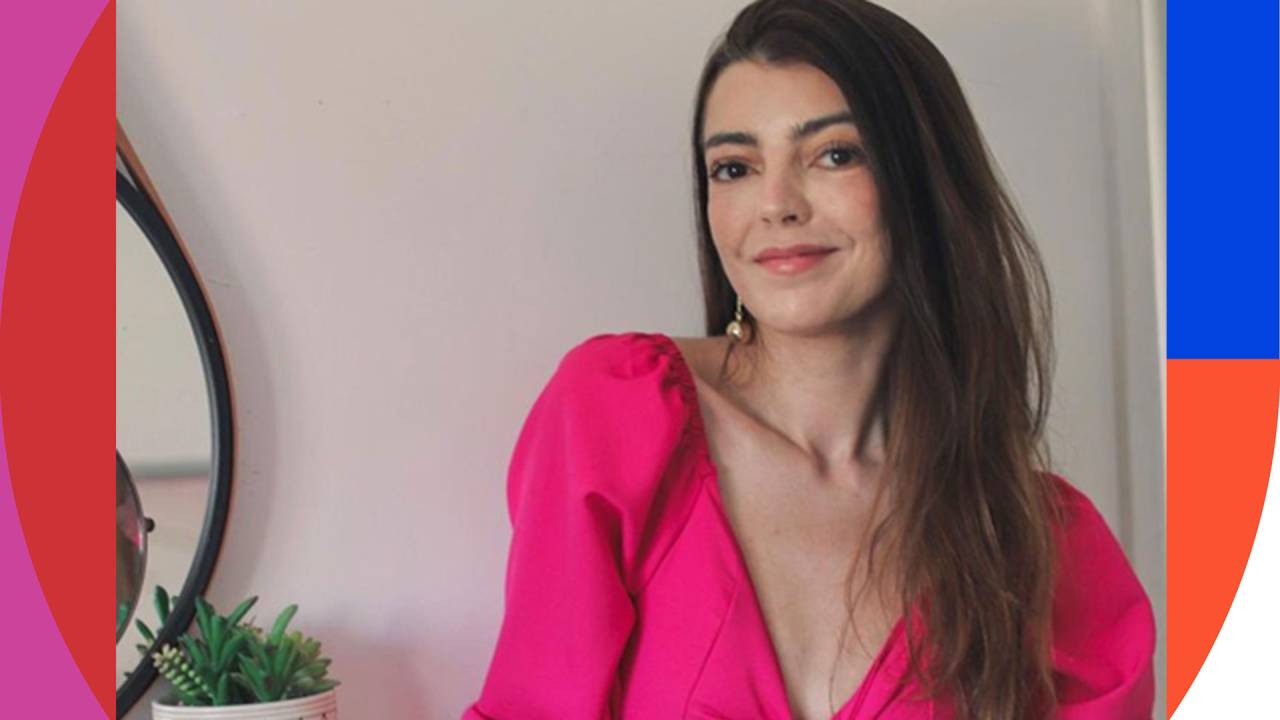 foto de Lia Camargo. Ela está sentada e olha para a câmera com um leve sorriso no rosto