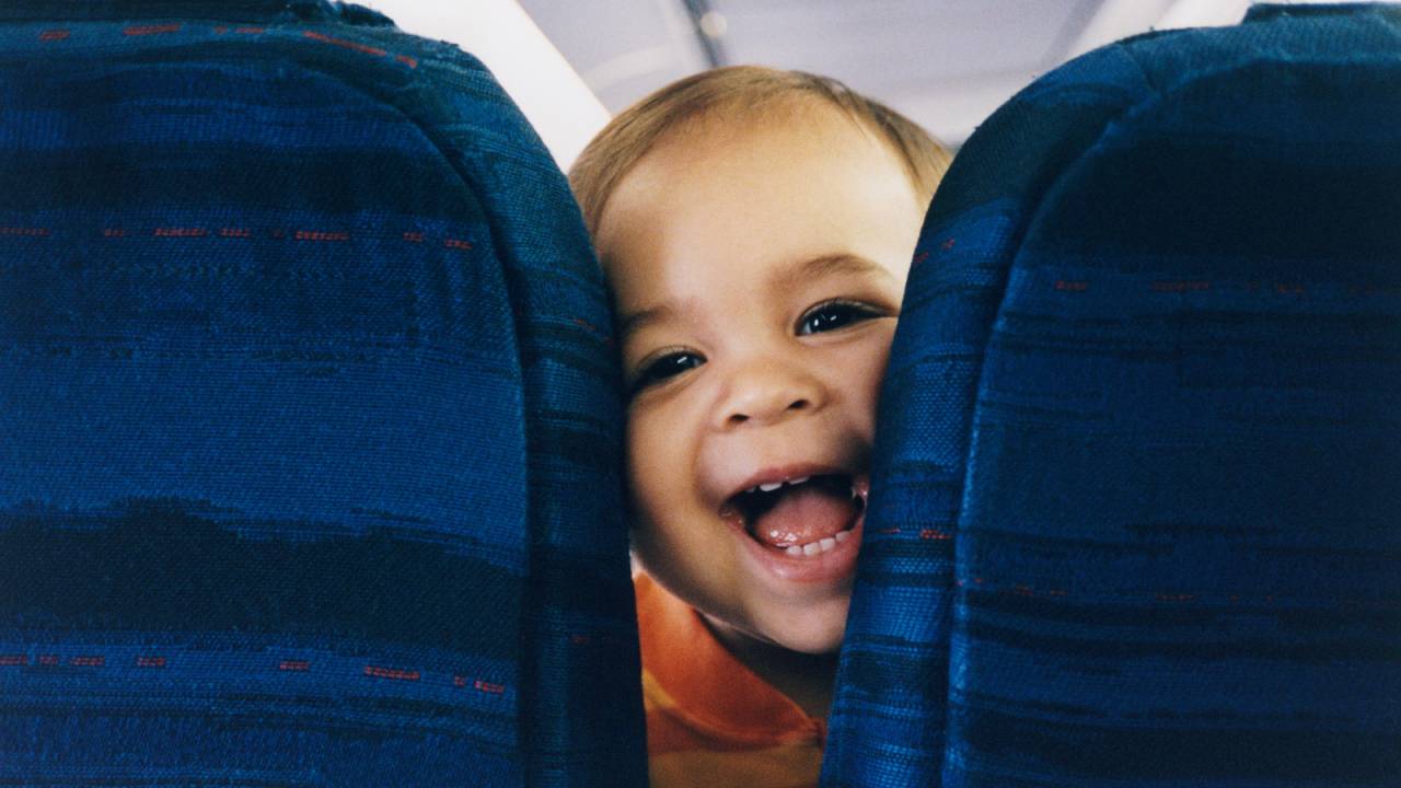 bebê sorrindo em cadeira de avião