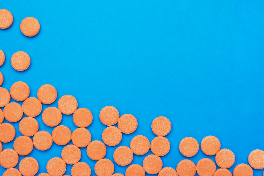 pílulas laranjas de vitamina c em cima de uma superfície azul