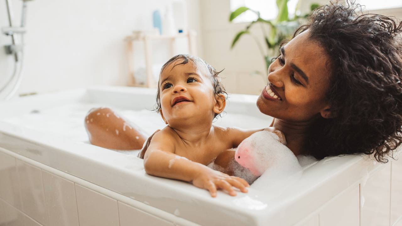 mãe e bebê tomando banho na banheira