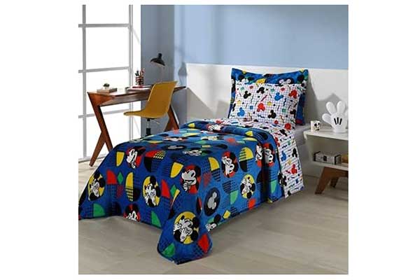 quarto infantil com foco na cama de solteiro sobre a qual há travesseiros, lençol e edredom coloridos, com estampas do personagem Mickey Mouse
