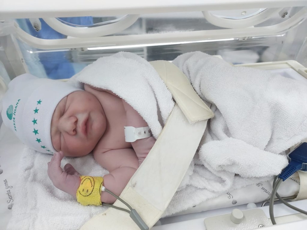 João Vitor, recém-nascido a termo na incubadora, com touca, pulseirinha do hospital, coberto com uma mantinha