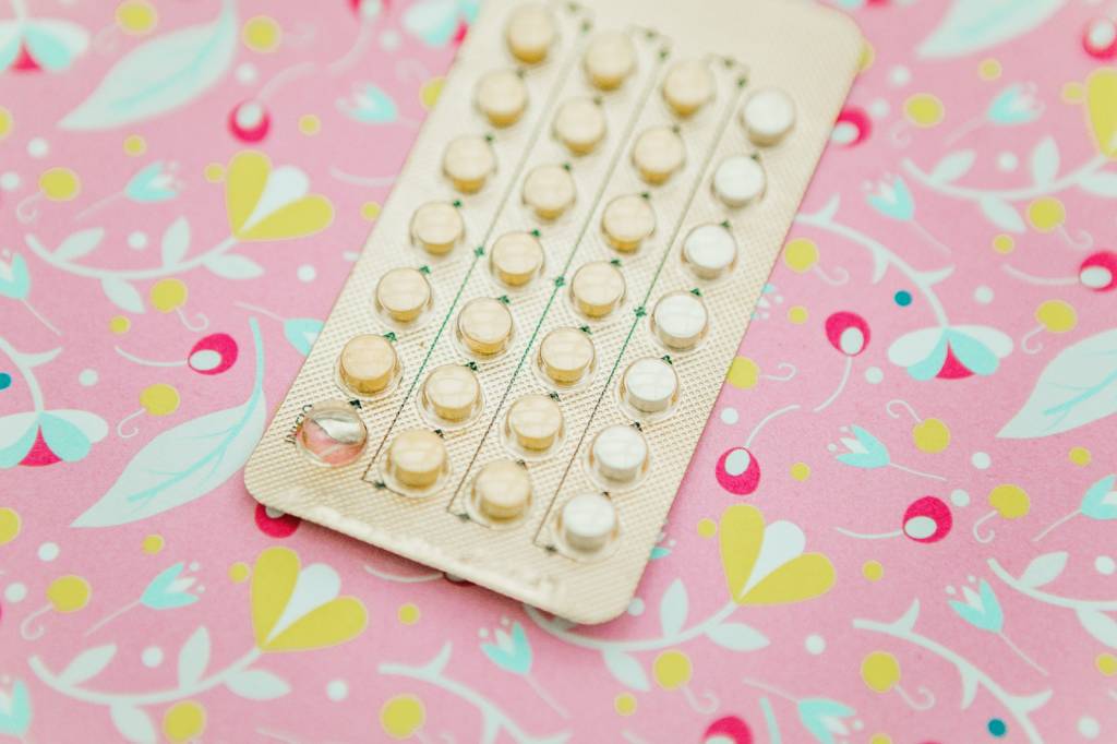 anticoncepcional sobre mesa com estampa rosa e amarela