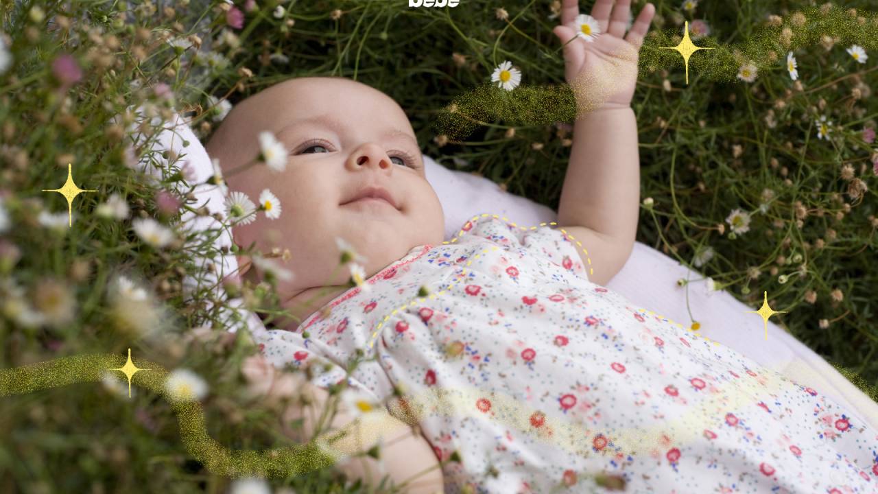 bebê deitado na grama brincando com flores