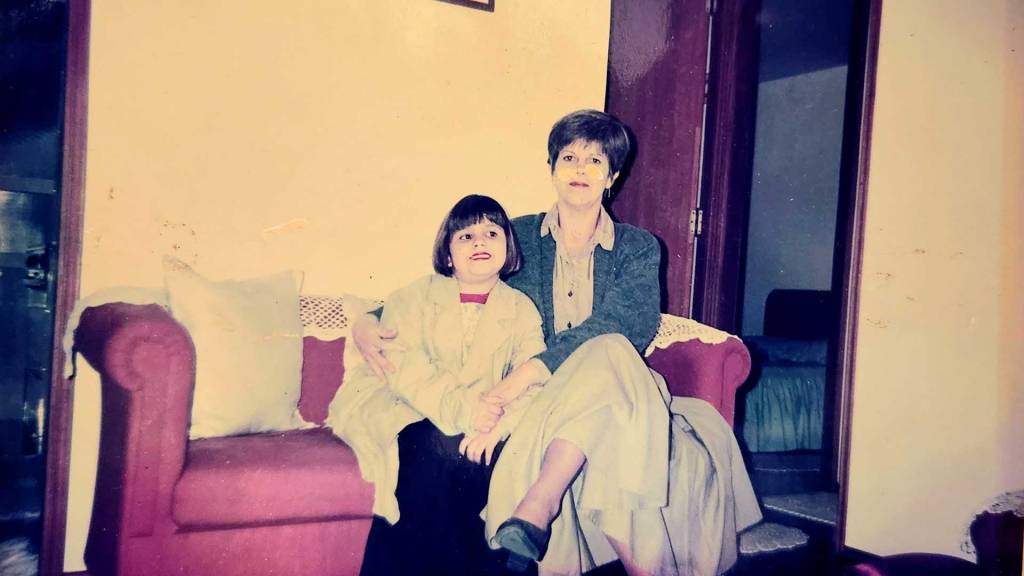 taina-goulart-e-a-mae-dialogos-de-uma-mae-solo garota e mulher sentadas em um sofá, abraçadas e olhando para a câmera