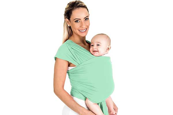 mulher segurando um bebê em um sling, um pedaço grande de tecido enrolado no corpo dela e da criança
