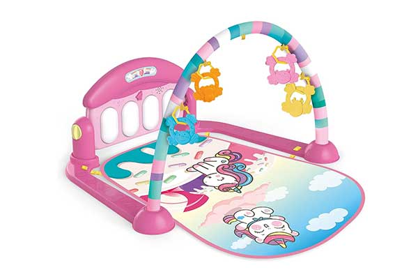 tapete colorido com estampa de unicórnios e peças que imitam o teclado de um piano e um arco suspenso com brinquedos pendurados