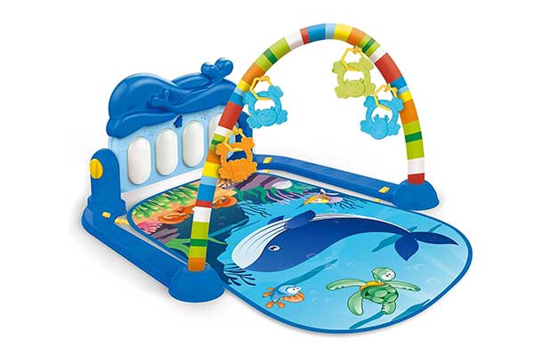 tapete colorido com estampa de animais no fundo do mar e peças que imitam o teclado de um piano e um arco suspenso com brinquedos pendurados