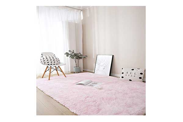 imagem de uma sala, com janela, cadeira, quadros no chão e um tapete felpudo