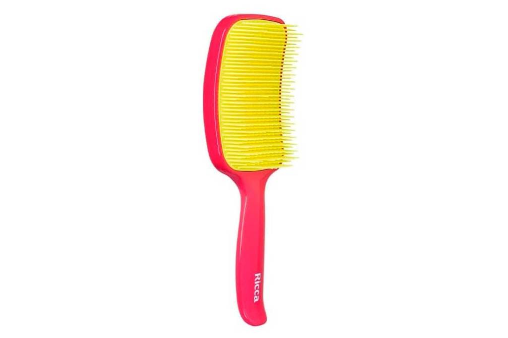 Escova de cabelo rosa com a parte das cerdas em amarelo. É grande e quadrada, com cabo.