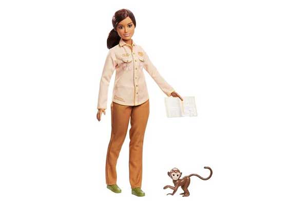 Barbie cuidadora da vida selvagem. Ela usa calça marrom e camisa bege, e segura um caderno. Ao lado dela há um macaco
